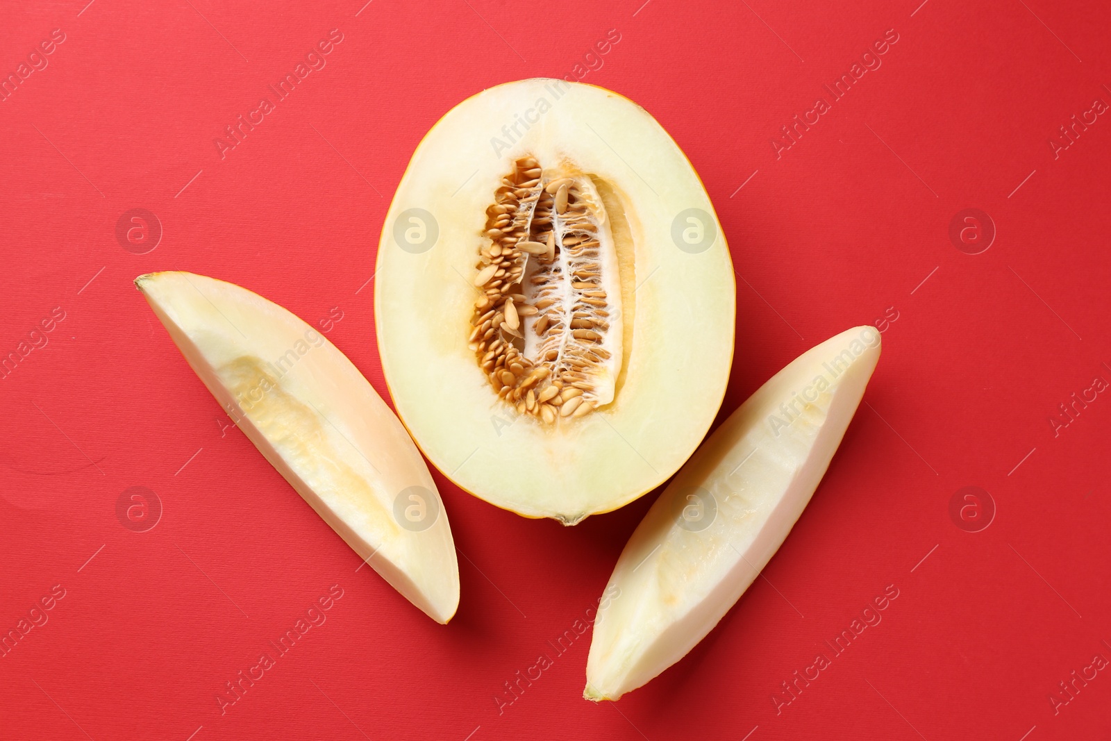 Photo of Fresh cut melon on red background, flat lay