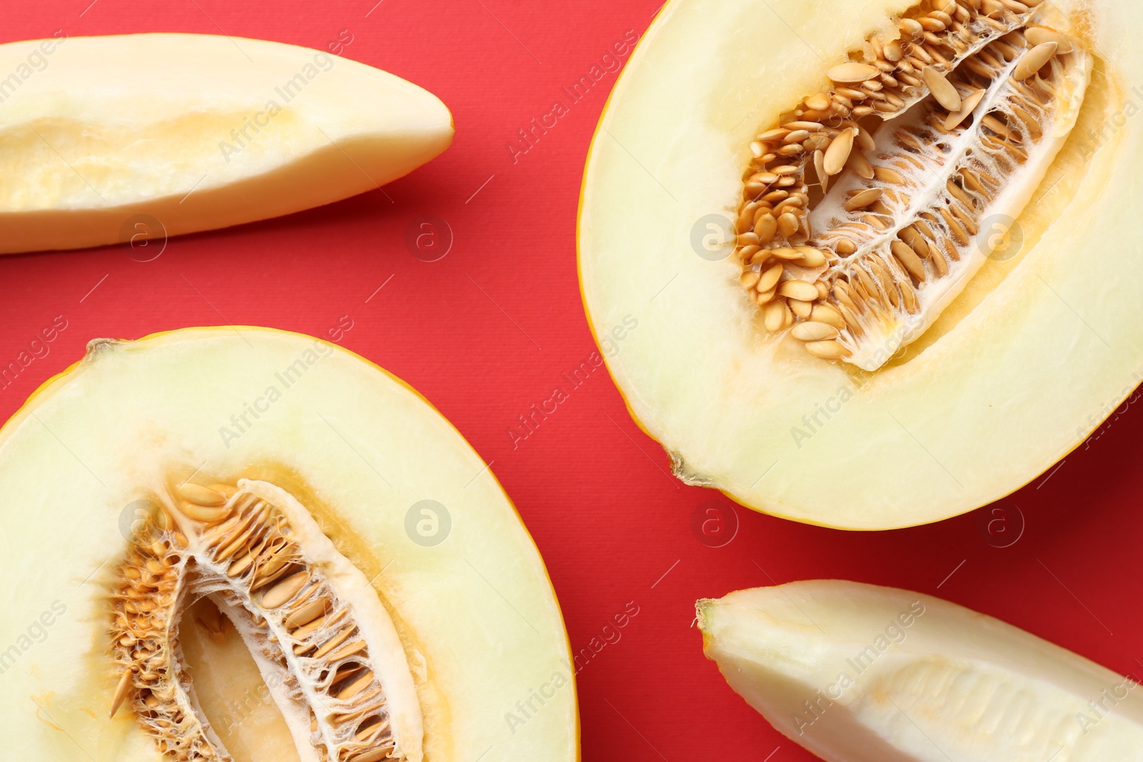 Photo of Fresh cut melons on red background, flat lay