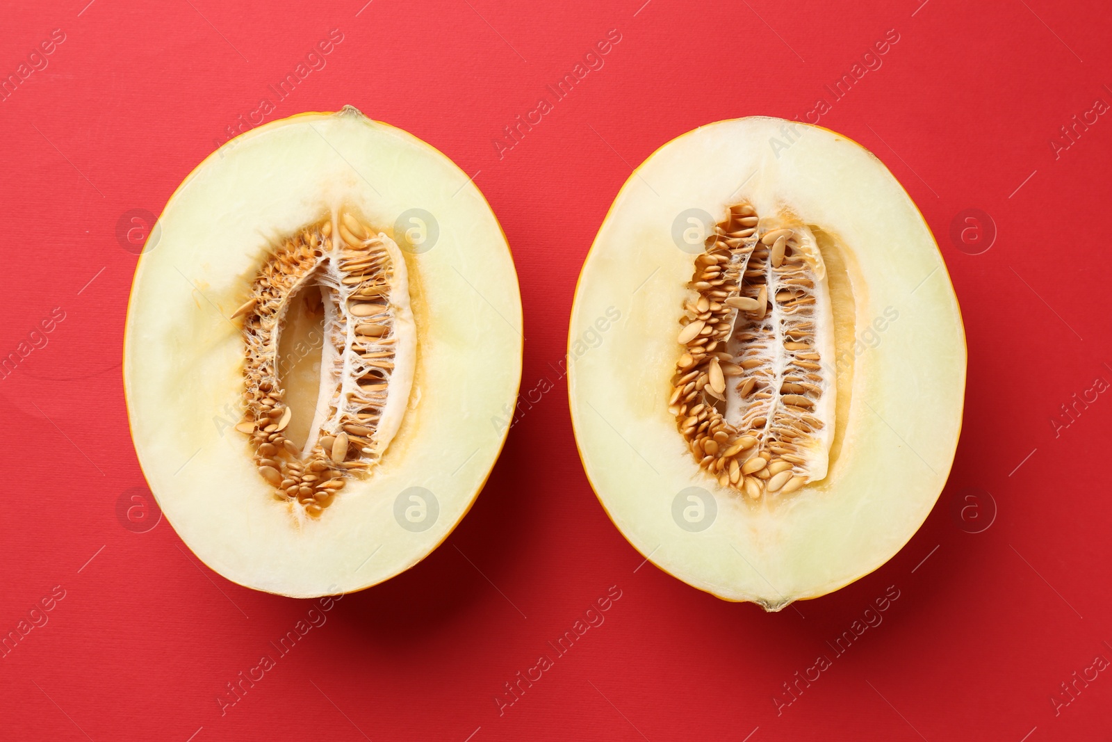 Photo of Halves of fresh melon on red background, top view