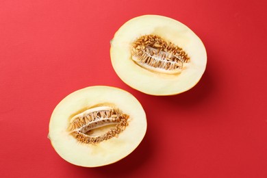 Photo of Halves of fresh melon on red background, top view