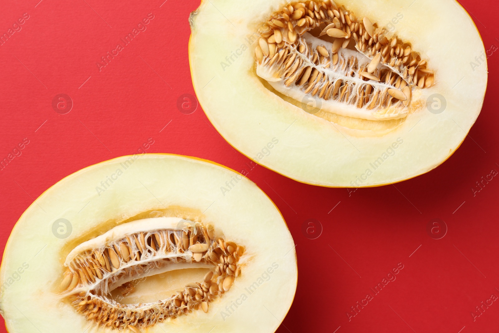 Photo of Halves of fresh melon on red background, top view