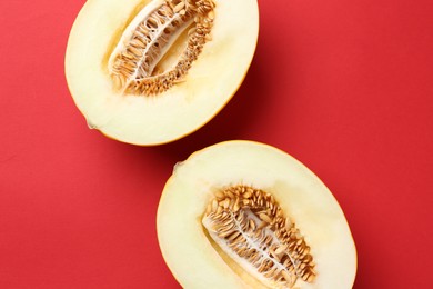 Photo of Halves of fresh melon on red background, top view