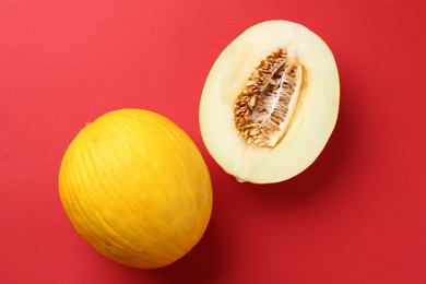 Whole and cut melons on red background, flat lay