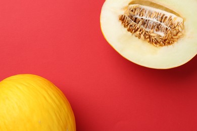 Whole and cut melons on red background, flat lay