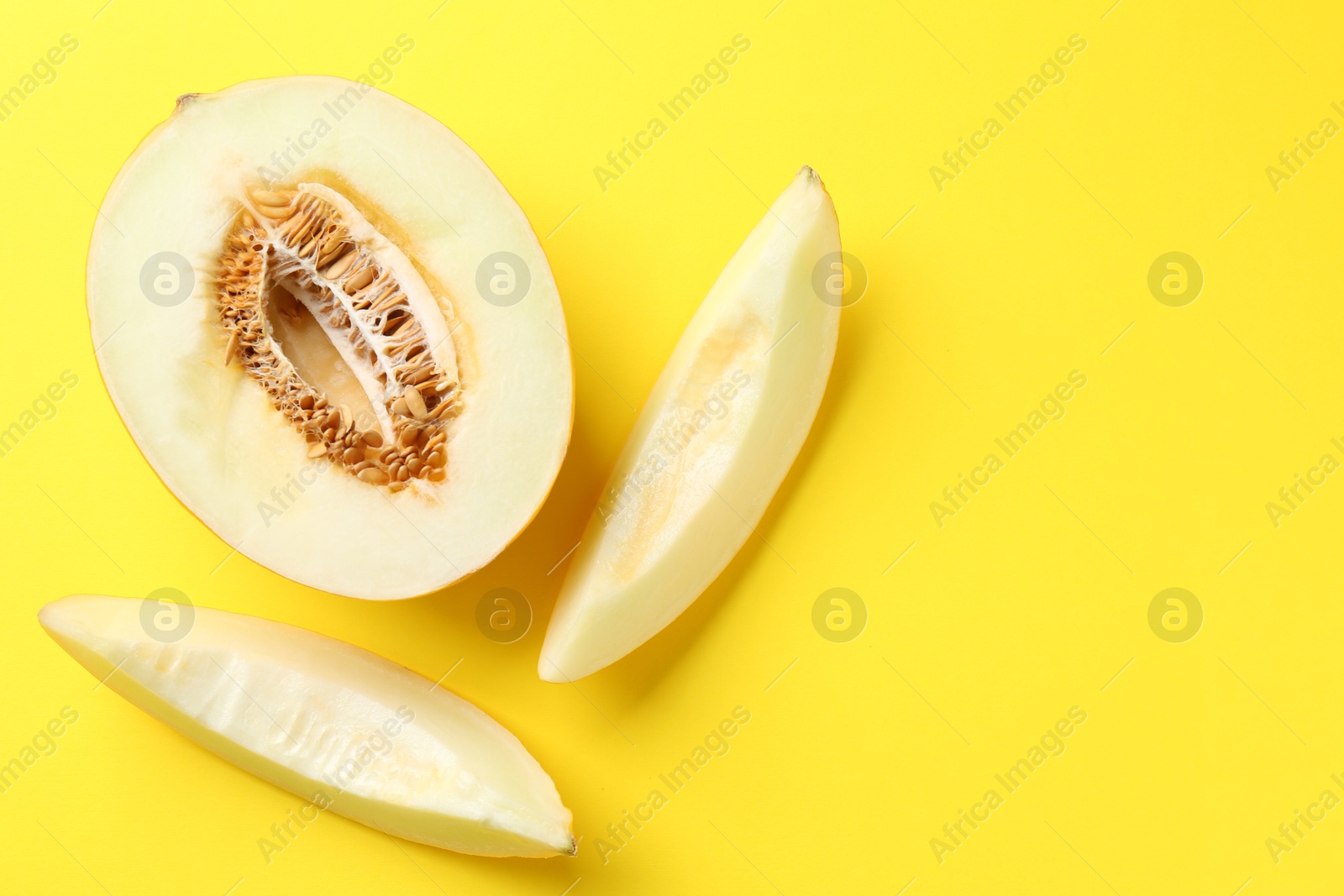 Photo of Fresh cut melon on yellow background, flat lay. Space for text