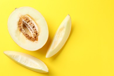 Photo of Fresh cut melon on yellow background, flat lay. Space for text