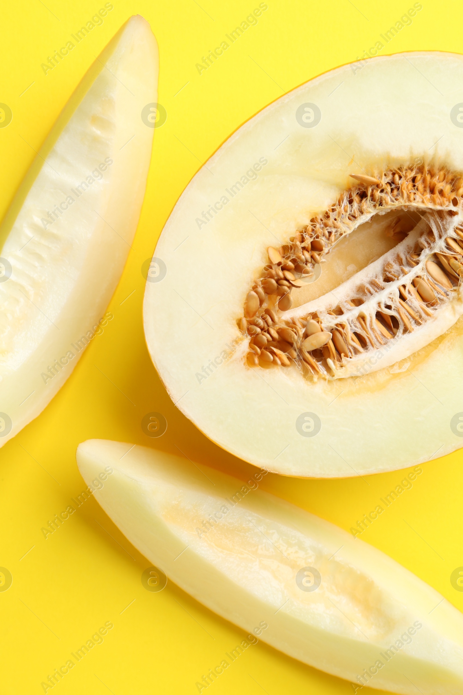 Photo of Fresh cut melon on yellow background, flat lay