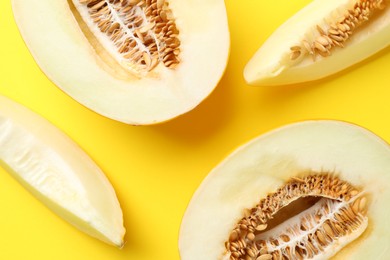 Photo of Fresh cut melons on yellow background, flat lay