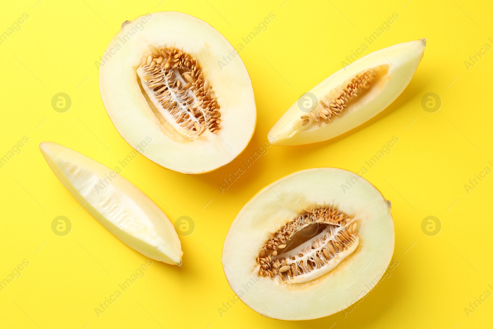 Photo of Fresh cut melons on yellow background, flat lay