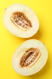 Photo of Halves of fresh melon on yellow background, top view