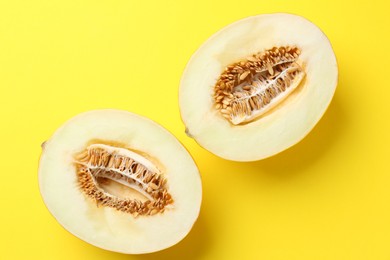 Photo of Halves of fresh melon on yellow background, top view