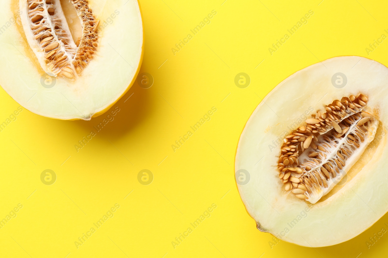 Photo of Halves of fresh melon on yellow background, top view