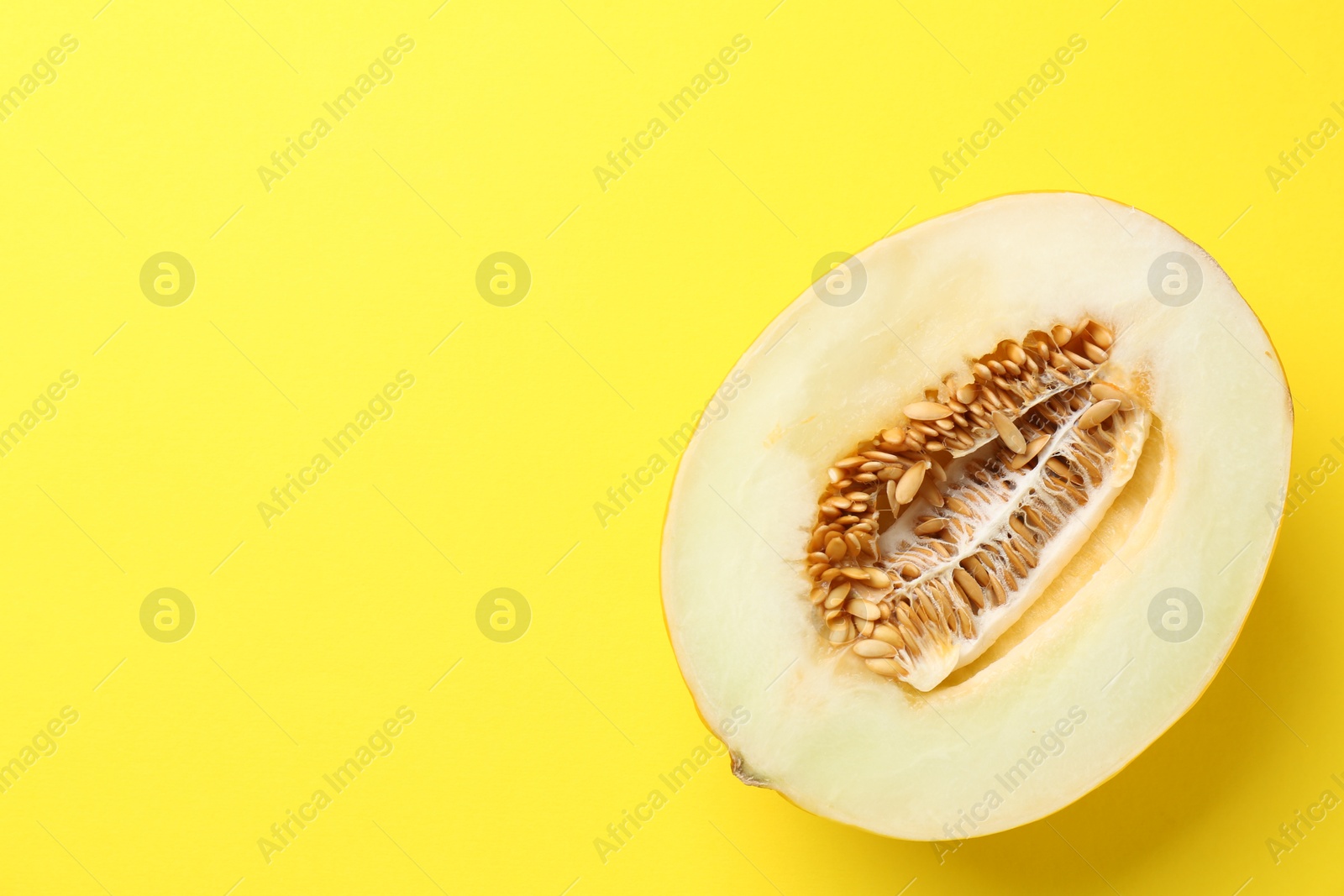 Photo of Half of fresh melon on yellow background, top view. Space for text