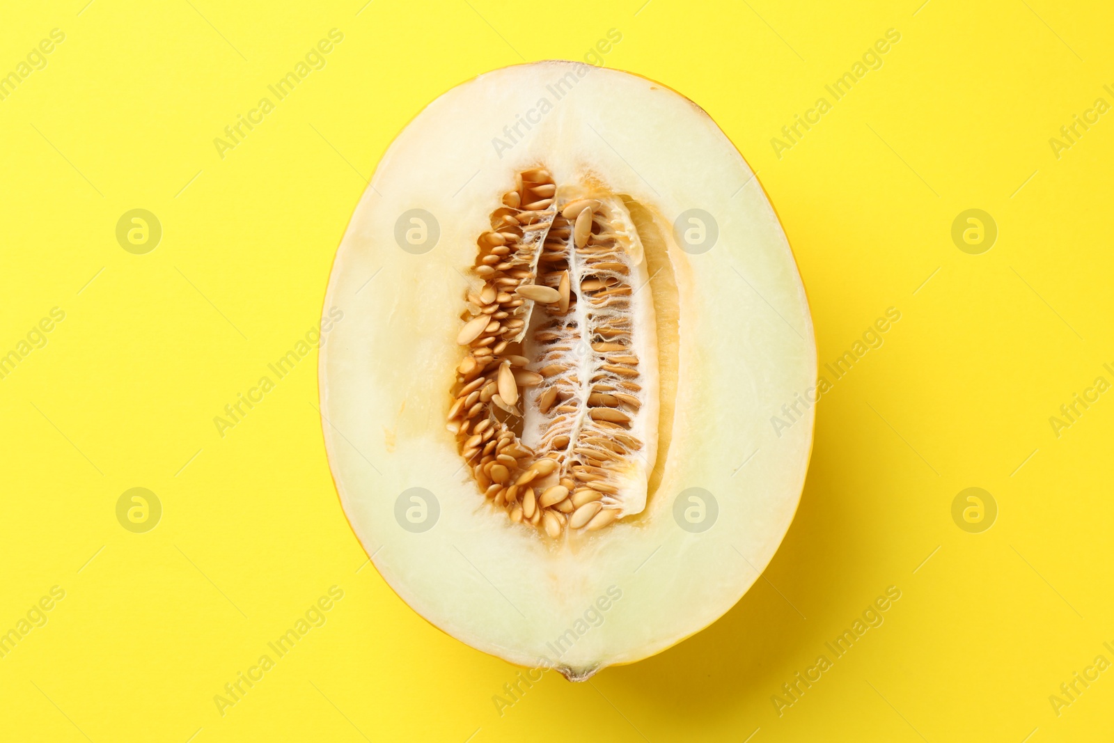 Photo of Half of fresh melon on yellow background, top view