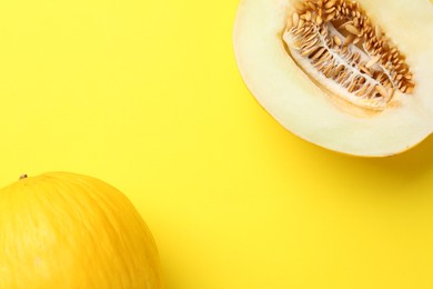 Photo of Whole and half of fresh melon on yellow background, flat lay