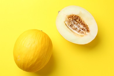 Photo of Whole and half of fresh melon on yellow background, flat lay