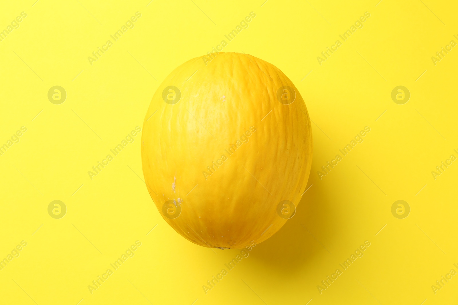 Photo of One fresh melon on yellow background, top view