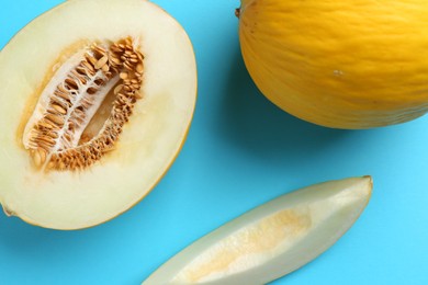 Whole and cut melons on light blue background, flat lay