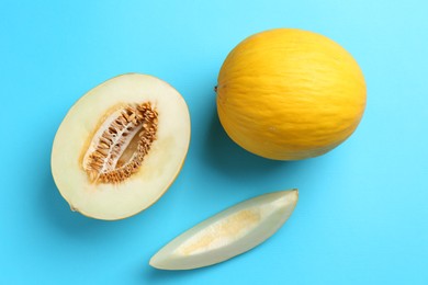 Photo of Whole and cut melons on light blue background, flat lay