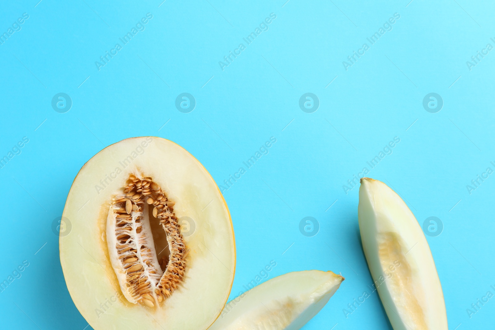 Photo of Fresh cut melon on light blue background, flat lay. Space for text