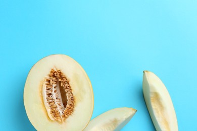 Photo of Fresh cut melon on light blue background, flat lay. Space for text