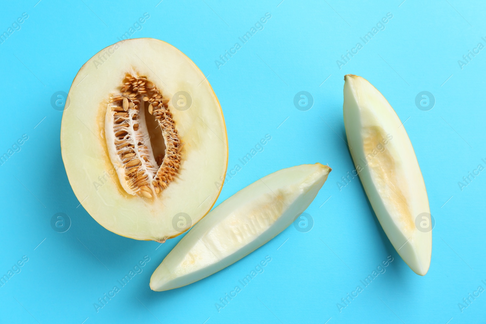 Photo of Fresh cut melon on light blue background, flat lay