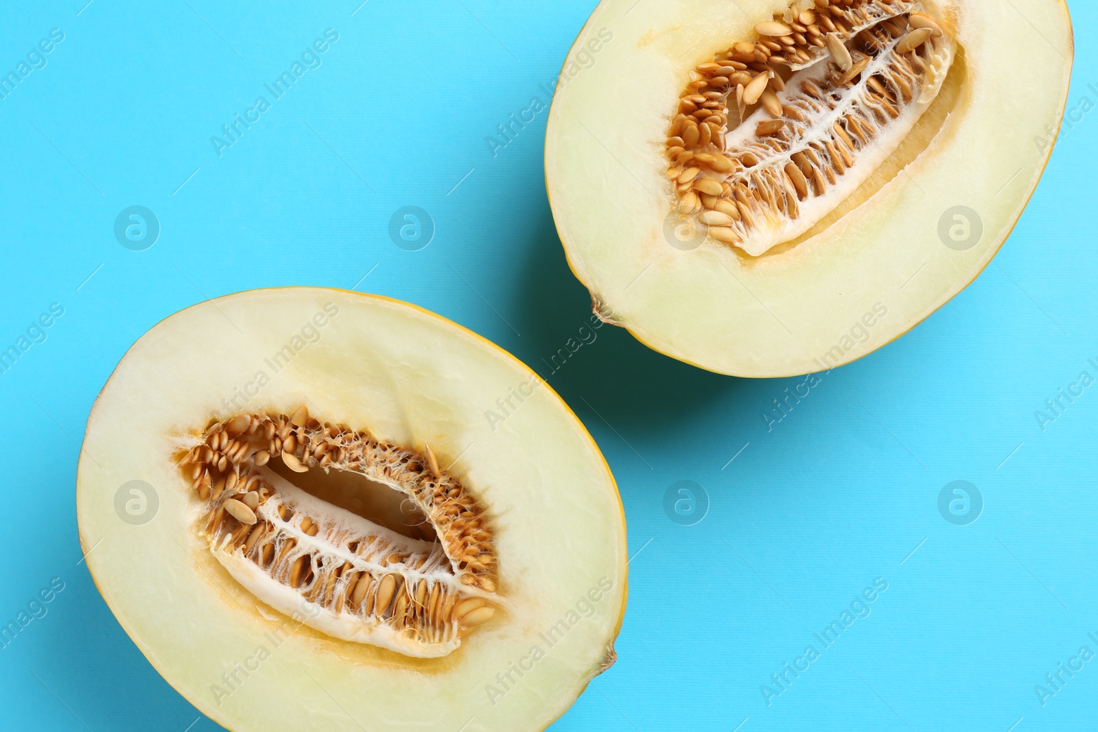 Photo of Halves of fresh melon on light blue background, top view