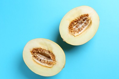 Halves of fresh melon on light blue background, top view