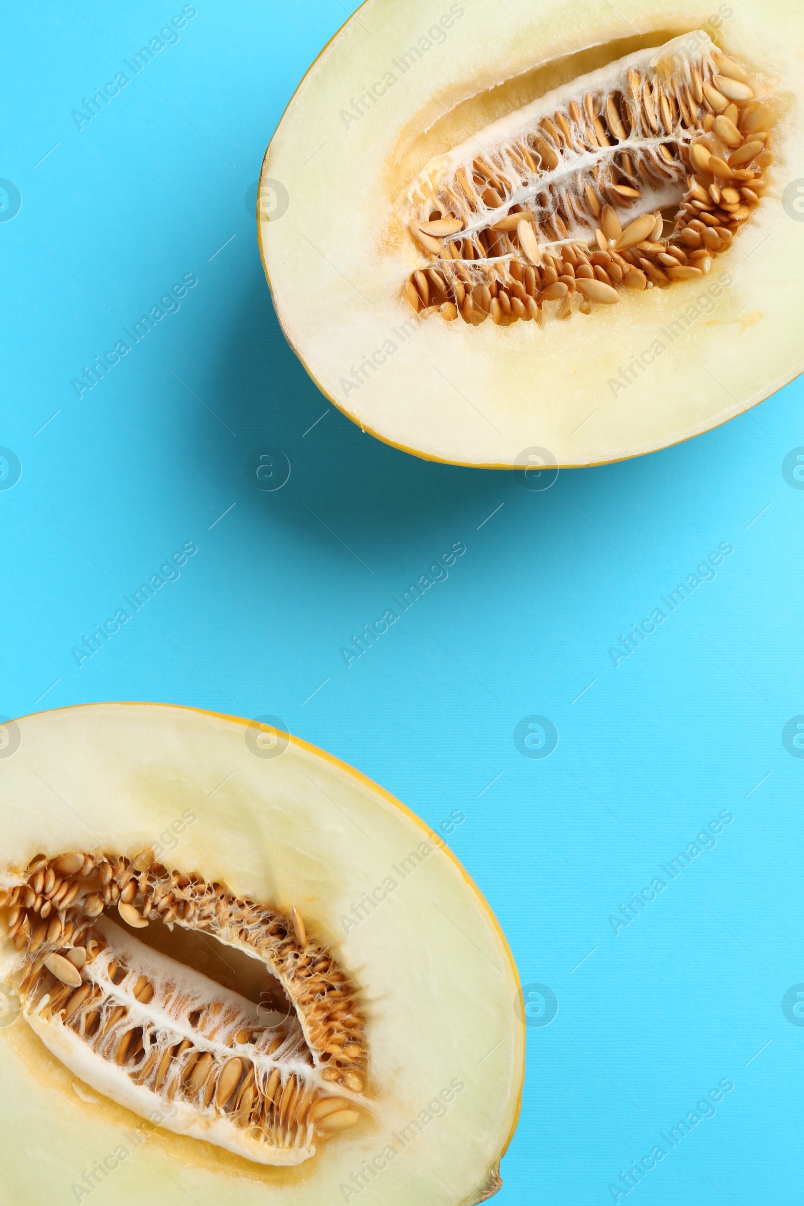 Photo of Halves of fresh melon on light blue background, top view