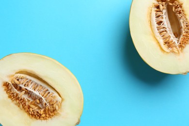 Photo of Halves of fresh melon on light blue background, top view