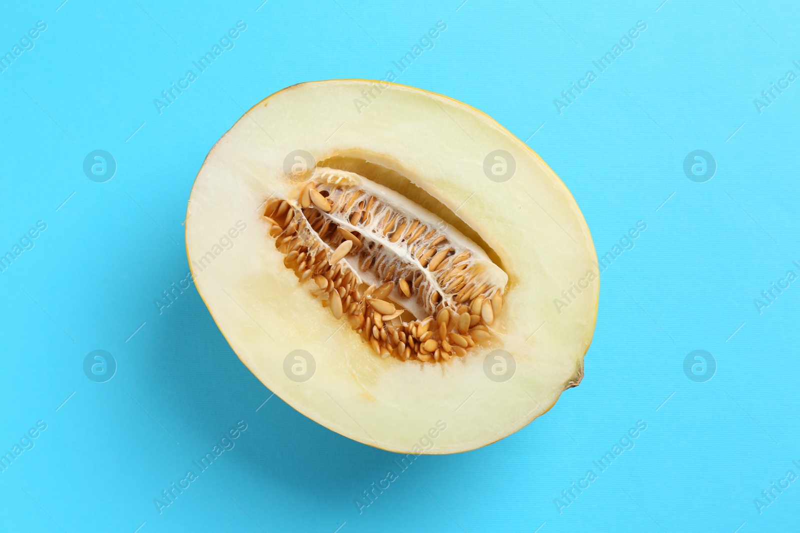 Photo of Half of fresh melon on light blue background, top view