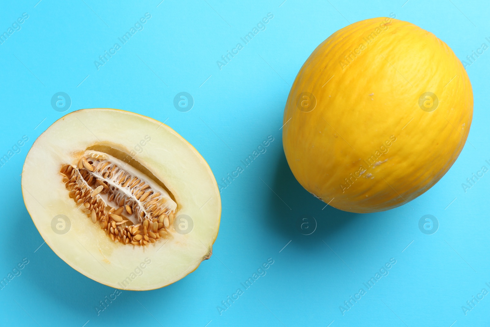 Photo of Whole and half of fresh melon on light blue background, flat lay