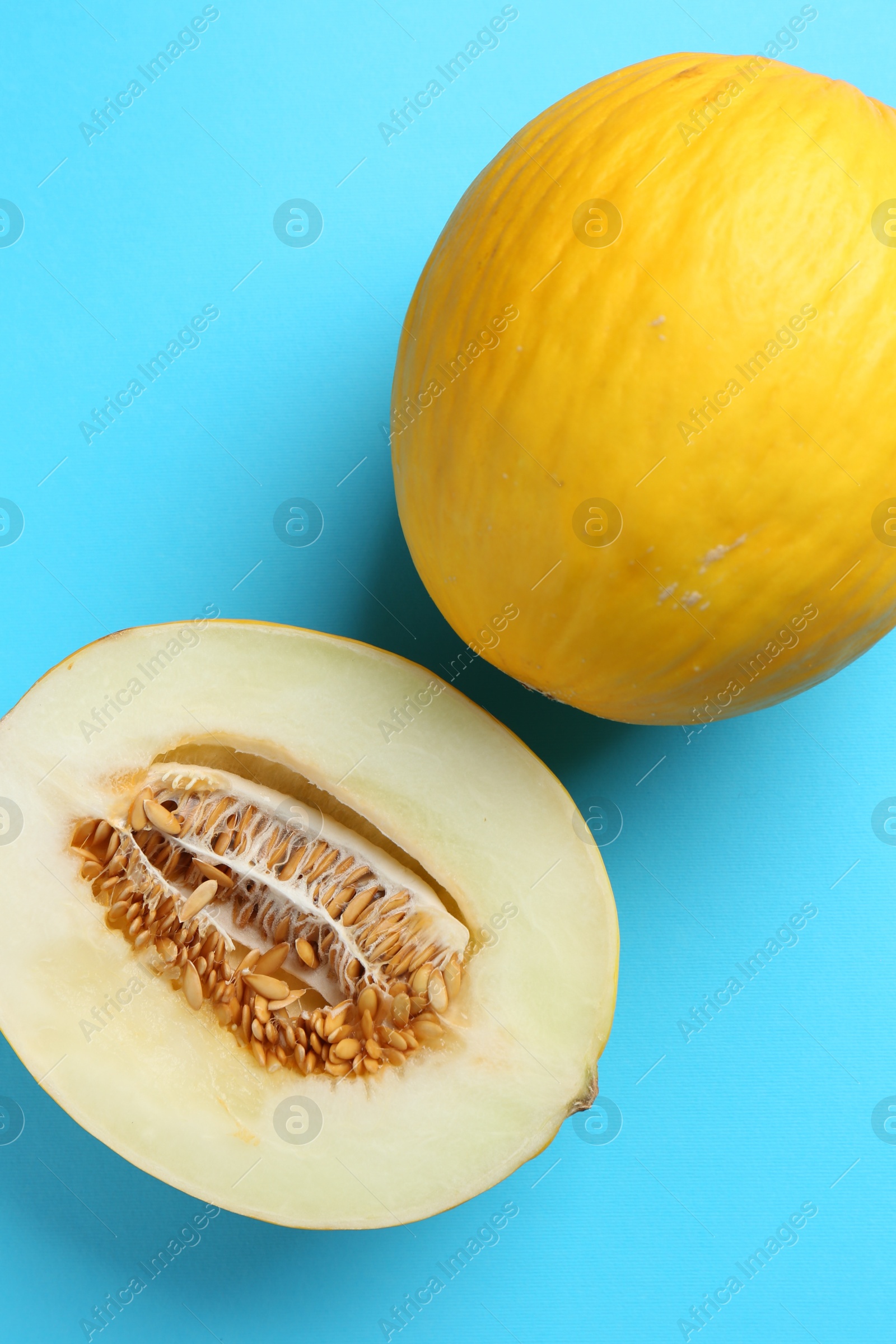 Photo of Whole and half of fresh melon on light blue background, flat lay