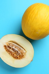 Whole and half of fresh melon on light blue background, flat lay