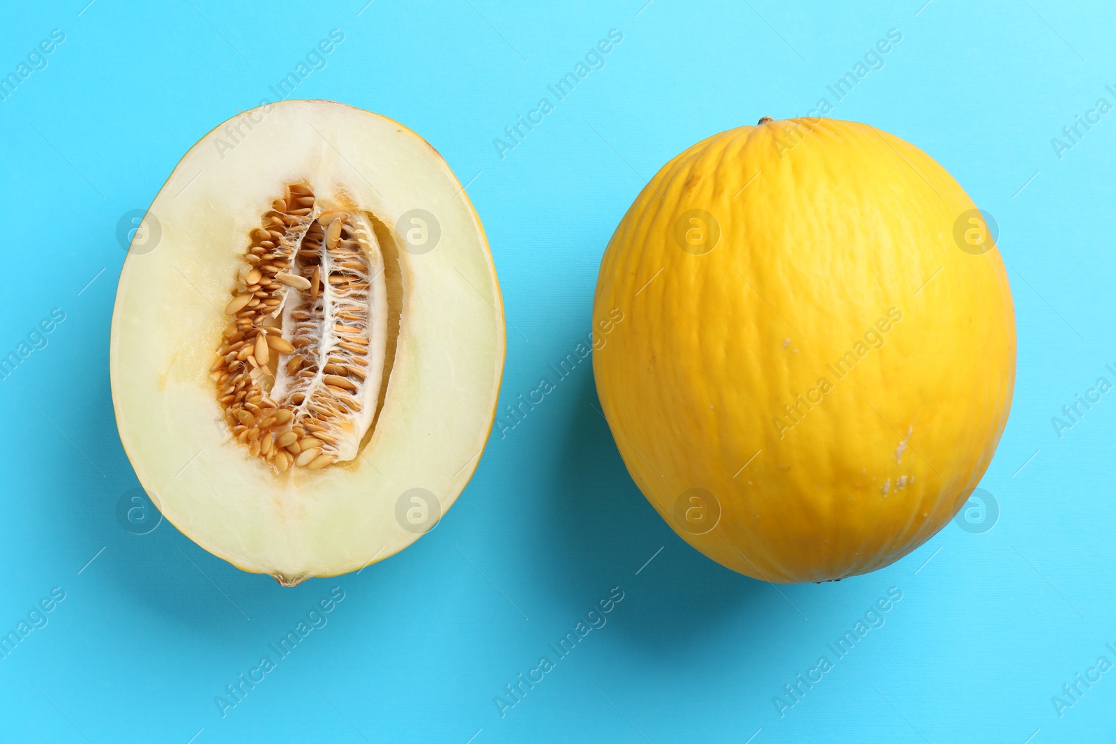 Photo of Whole and half of fresh melon on light blue background, flat lay