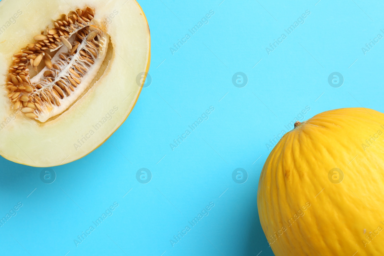 Photo of Whole and half of fresh melon on light blue background, flat lay