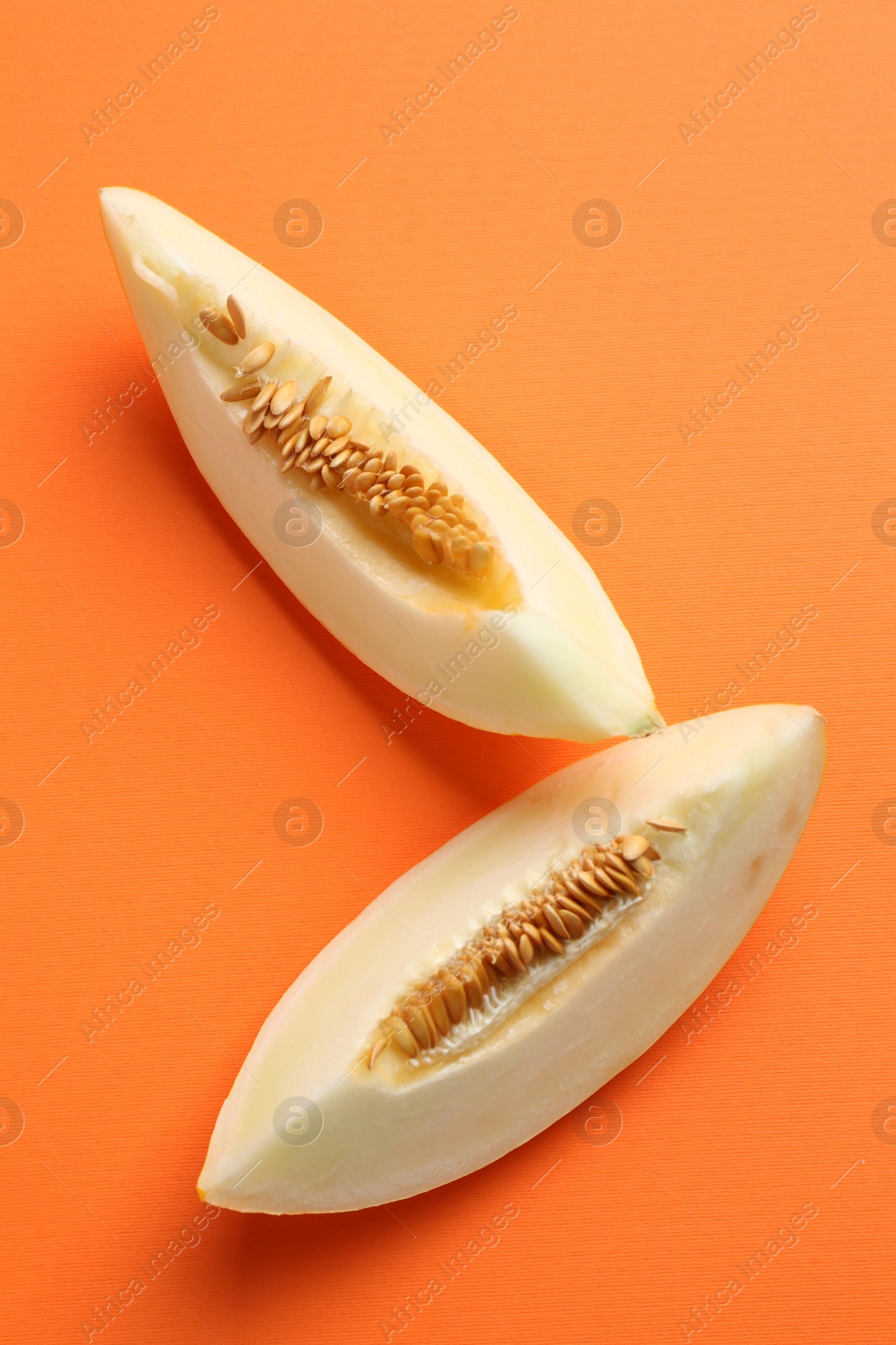 Photo of Fresh cut melon on orange background, top view