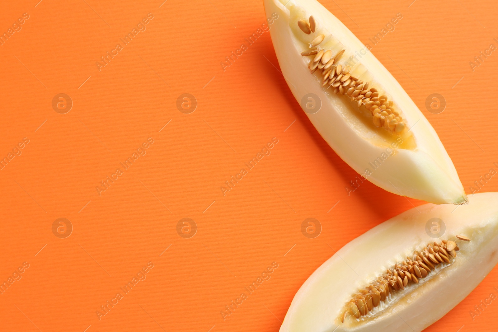 Photo of Fresh cut melon on orange background, top view. Space for text