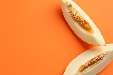 Photo of Fresh cut melon on orange background, top view. Space for text