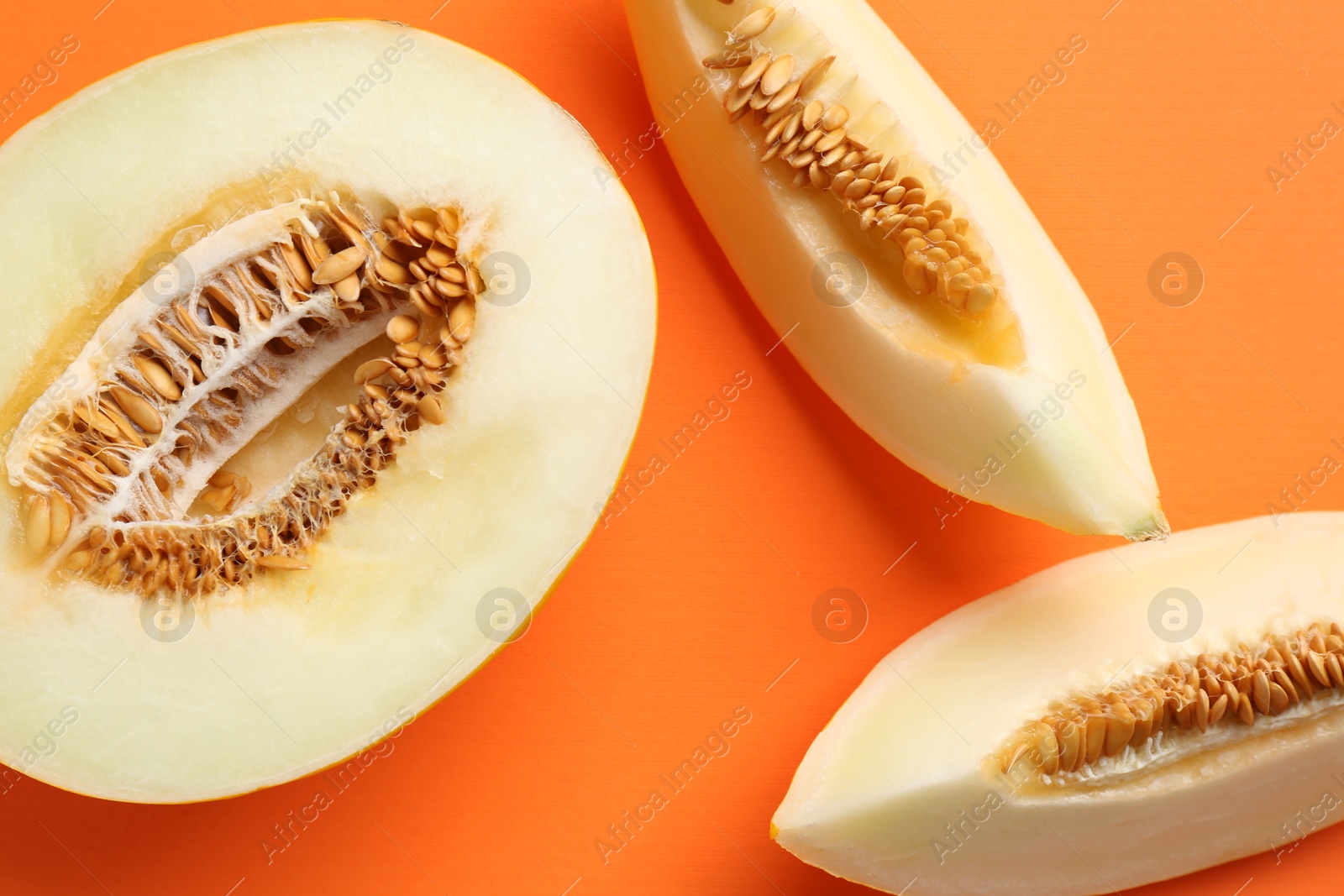 Photo of Fresh cut melon on orange background, flat lay