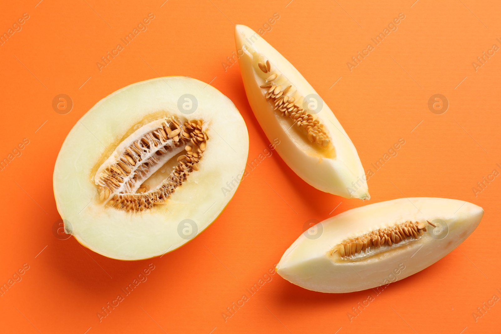 Photo of Fresh cut melon on orange background, flat lay