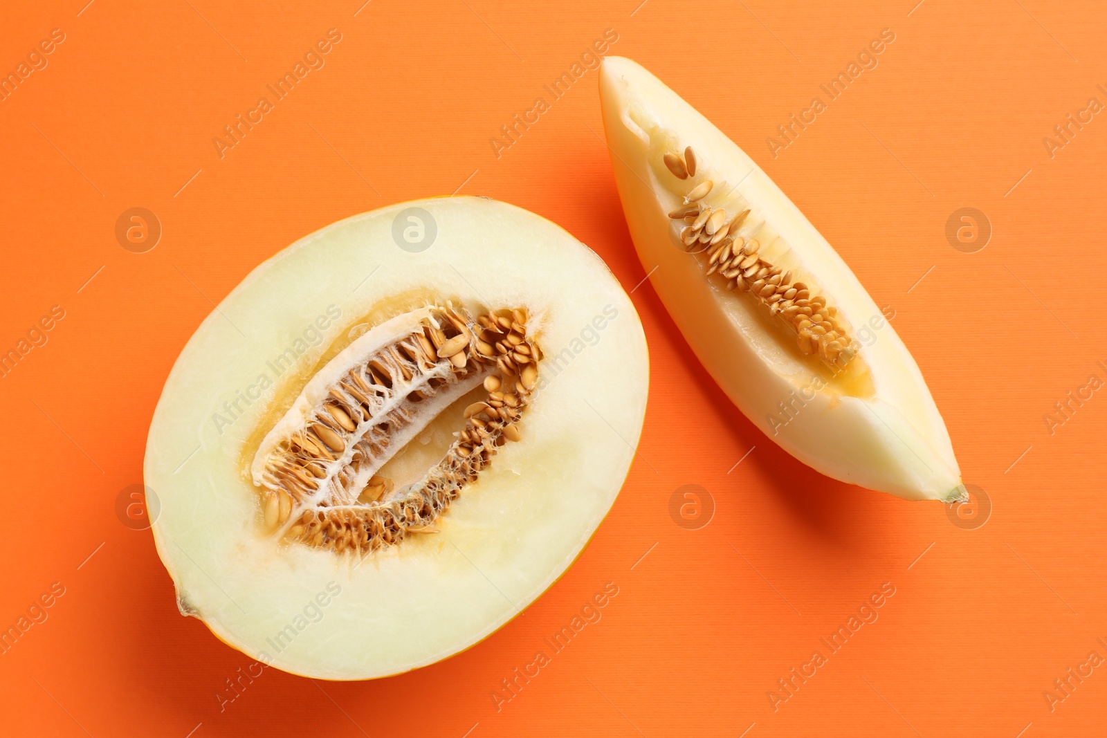 Photo of Fresh cut melon on orange background, flat lay