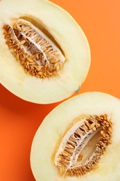 Halves of fresh melon on orange background, top view