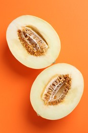 Halves of fresh melon on orange background, top view