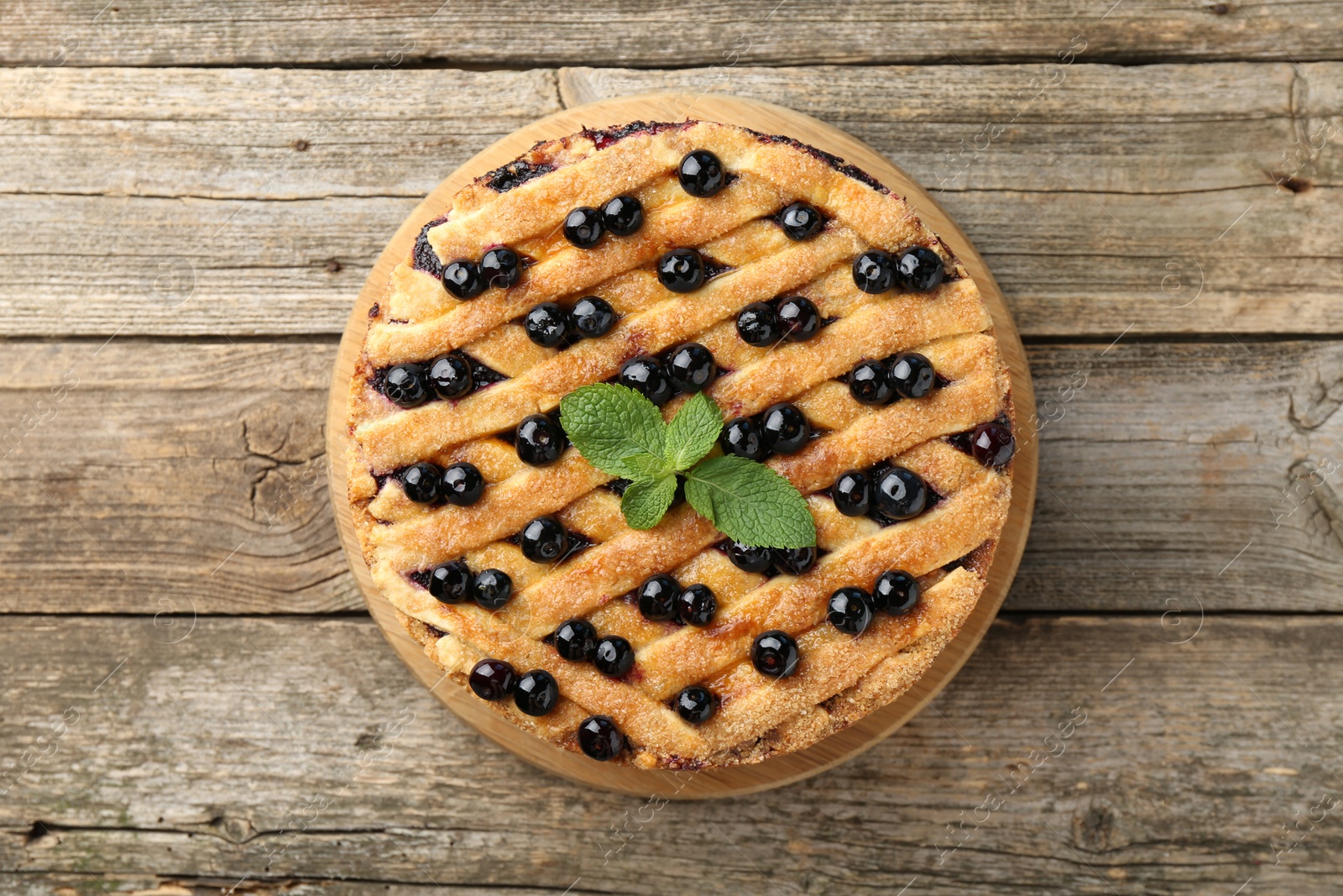 Photo of Delicious homemade blueberry pie with mint on wooden table, top view