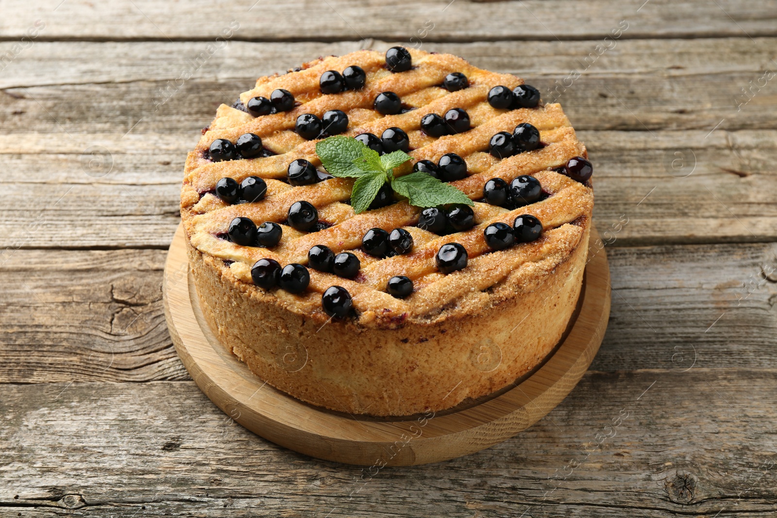 Photo of Delicious homemade blueberry pie with mint on wooden table