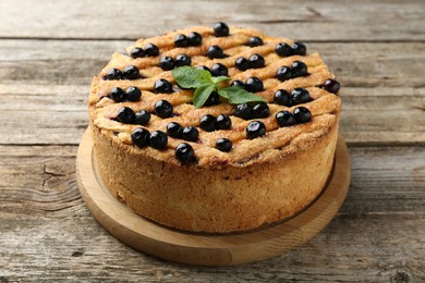 Photo of Delicious homemade blueberry pie with mint on wooden table, closeup