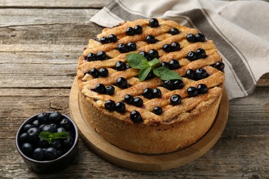 Photo of Delicious homemade blueberry pie with mint and fresh berries on wooden table