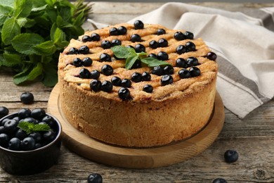 Photo of Delicious homemade blueberry pie with mint and fresh berries on wooden table