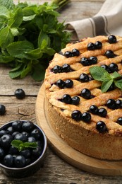 Photo of Delicious homemade blueberry pie with mint and fresh berries on wooden table